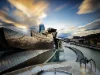 Un edificio moderno e scultoreo con un fiume che scorre sullo sfondo al tramonto.