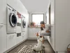 Una donna gioca con un cane in una moderna lavanderia di Nolte Utility Rooms.