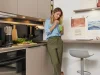 Una donna in una moderna cucina Nolte beve un frullato verde.
