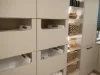 Una lavanderia con armadi beige e cesti, presentata da Nolte Utility Rooms.