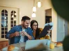 Una coppia fa colazione al tavolo con laptop e documenti.