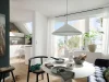 Un luminoso soggiorno con tavolo da pranzo e angolo cottura, circondato da piante, presenta Nolte Living.
