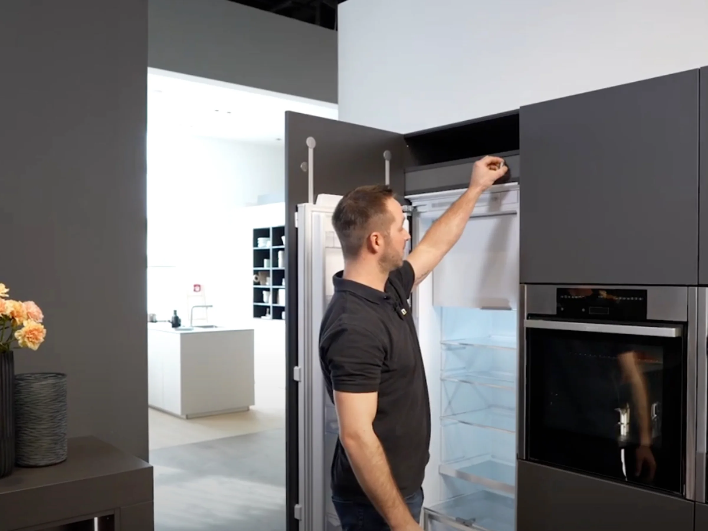 Un uomo apre un frigorifero in una cucina moderna di Nolte Kitchen.