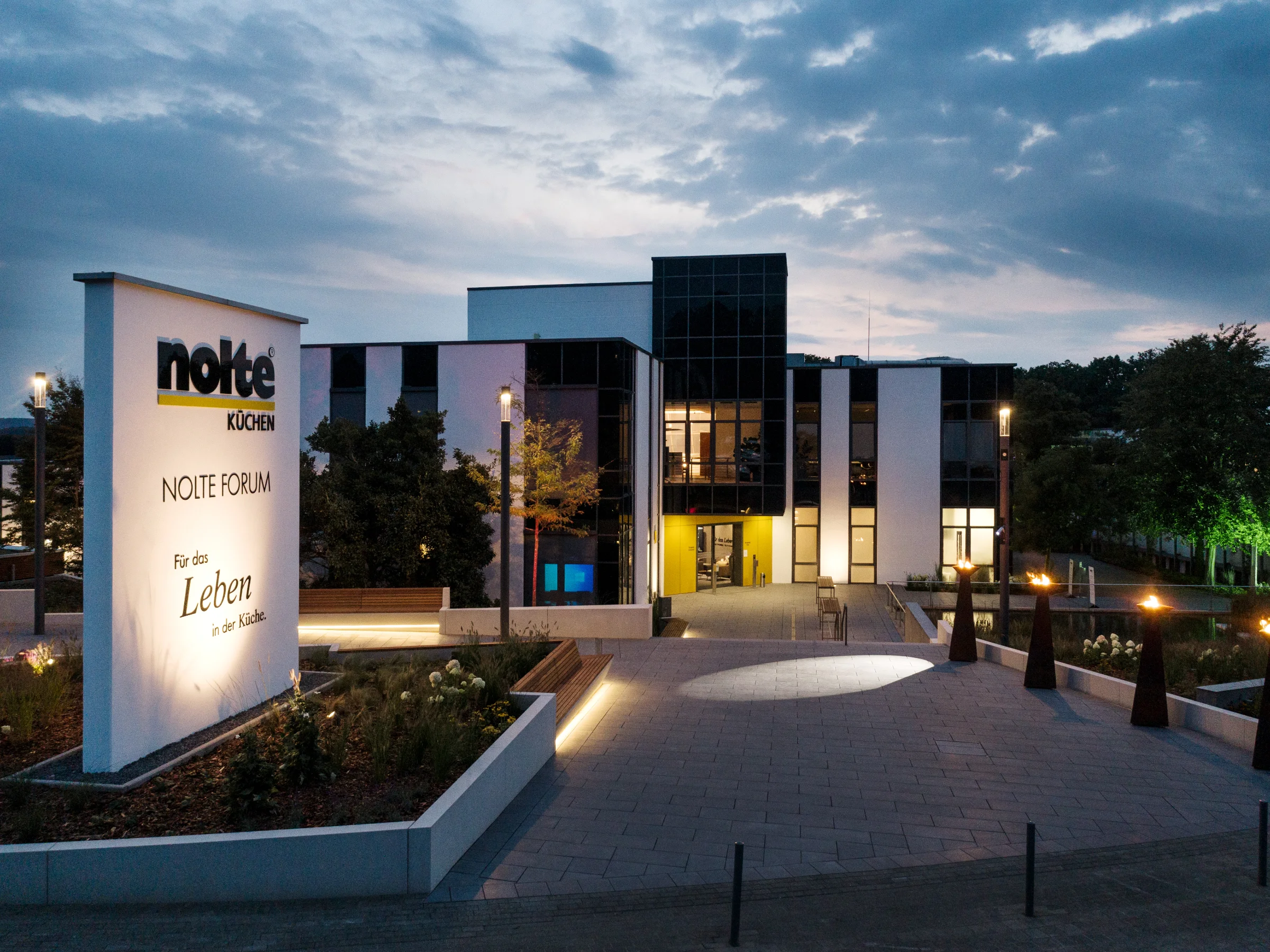 Edificio moderno al crepuscolo con insegna illuminata di Nolte Kitchen in primo piano.