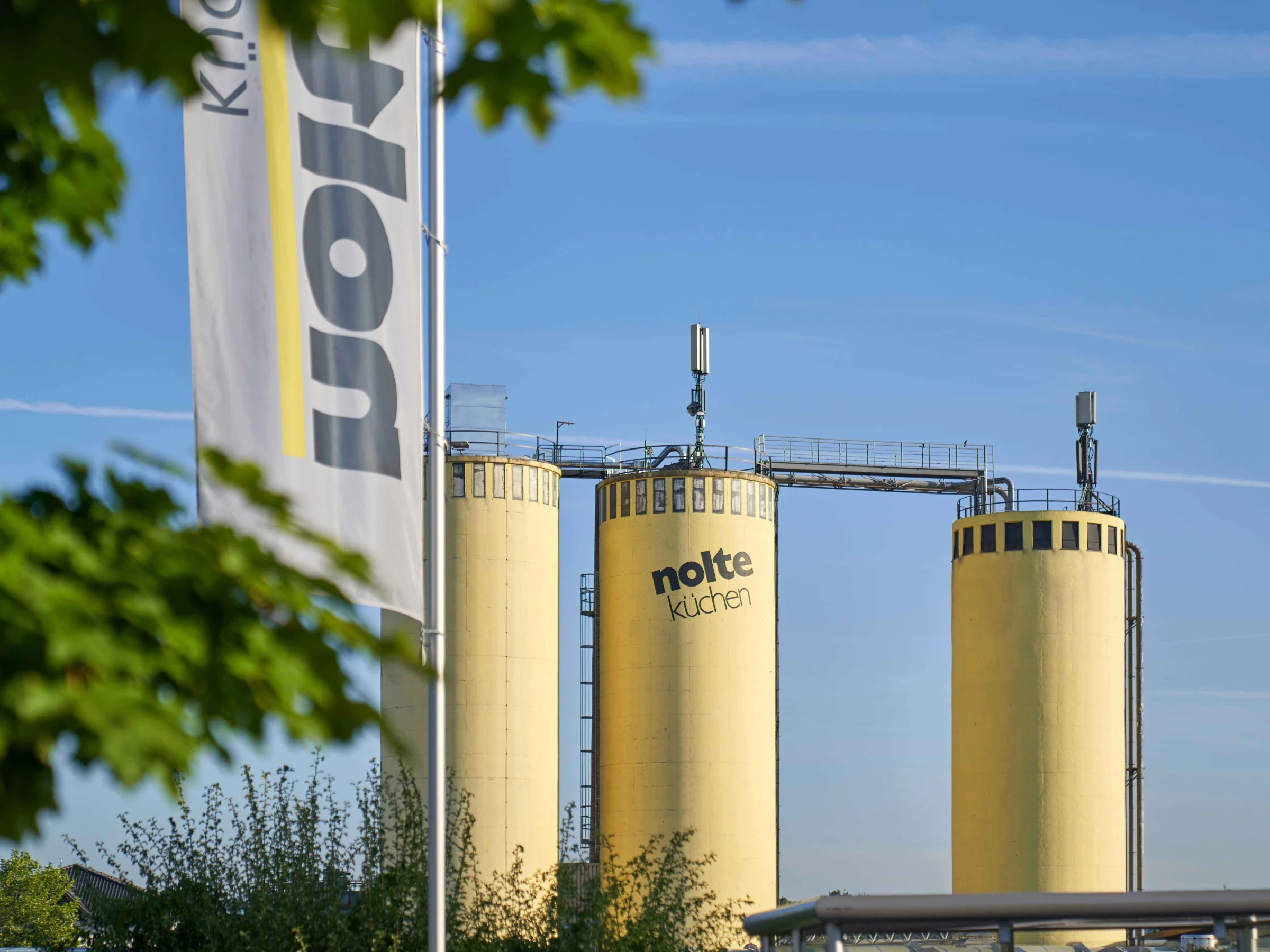 Three yellow silos with Nolte Kitchen logo against a blue sky.