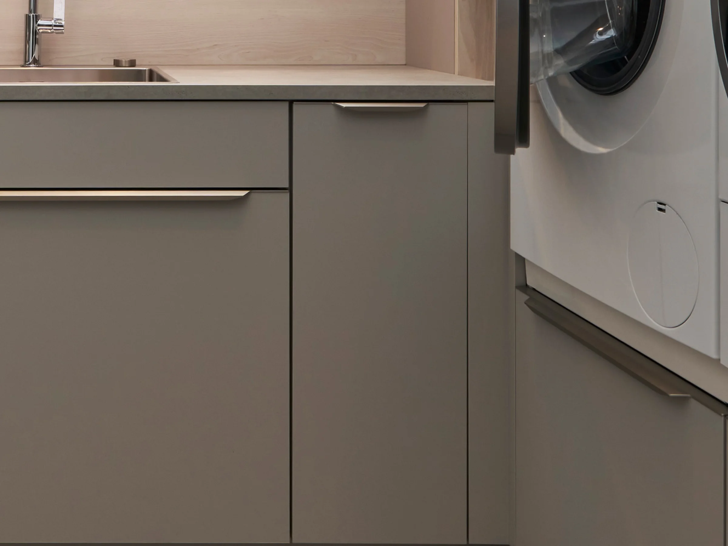 Moderna lavanderia con armadi grigi e lavatrice, Nolte Utility Rooms.