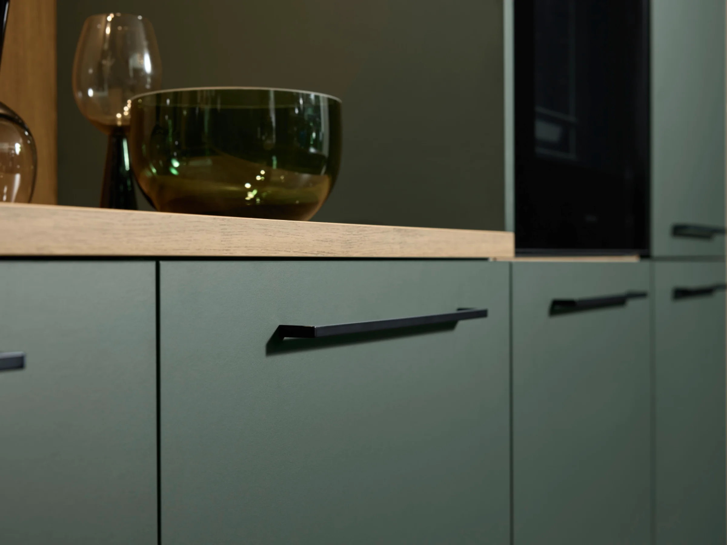 Armadi da cucina moderni con frontali verdi e maniglie nere di Nolte Kitchen.