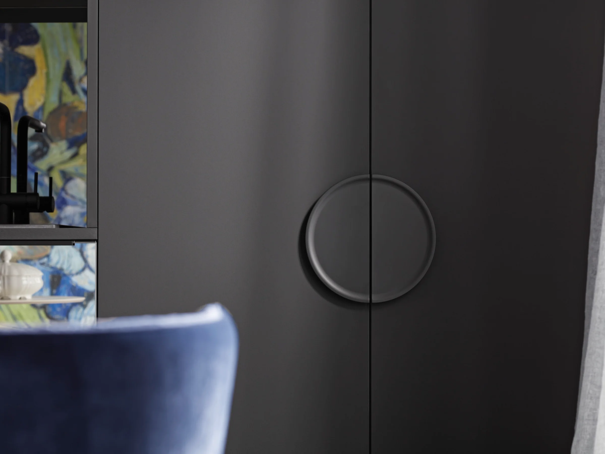 Elegante credenza con maniglia rotonda accanto a sedia blu, parte della collezione Nolte Living.