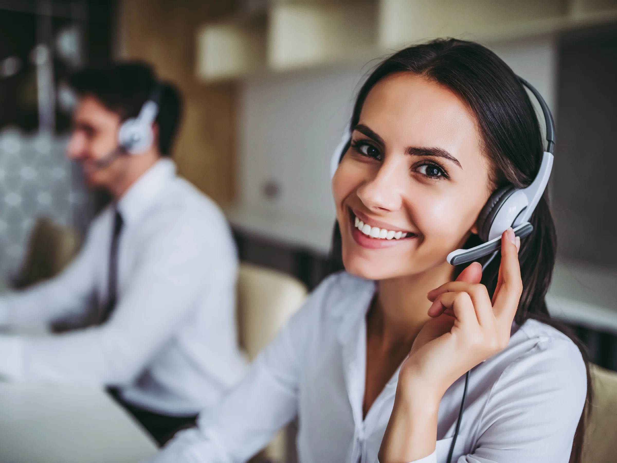 Due persone lavorano in un ufficio moderno con cuffie.