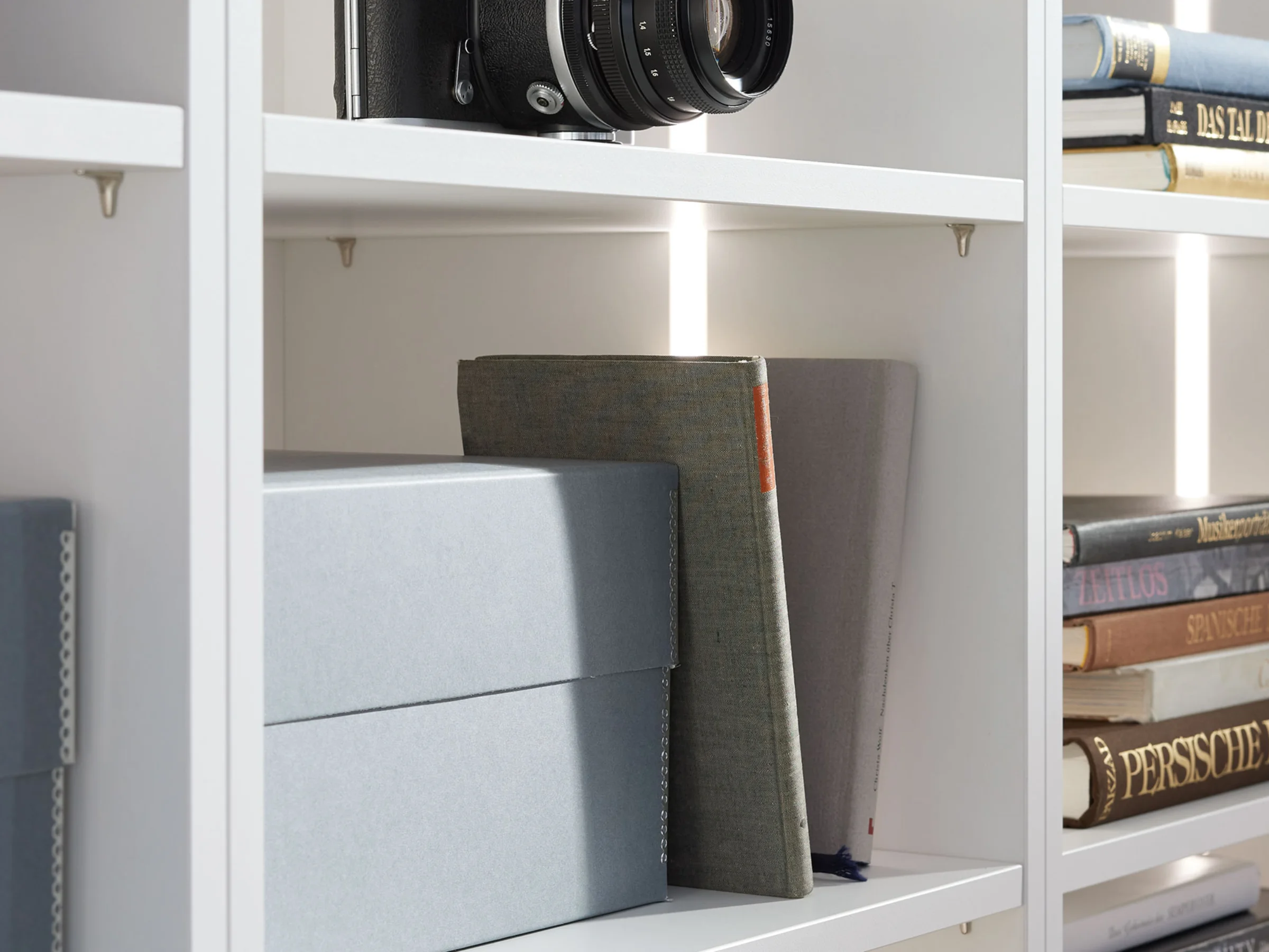 Scaffale bianco con libri e scatole, parte della collezione Nolte Living.