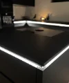 Cucina moderna nera con isola illuminata, progettata da Nolte Kitchen.