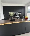 Cucina moderna con armadi scuri e isola, decorata con fiori, di Nolte Kitchen.