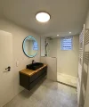 Bagno moderno con lavabo nero e illuminazione a specchio rotonda, Nolte SPA.