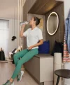 Donna in abbigliamento sportivo beve acqua in un soggiorno moderno con Nolte Living.