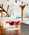 Cucina moderna con travi in legno e sedie rosse sotto una finestra sul tetto. Nolte Kitchen.