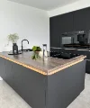 Cucina moderna con armadi scuri e accenti in legno, arredata da Nolte Kitchen.
