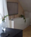 In un moderno soggiorno c'è una credenza bianca decorata con piante sotto una TV a parete. Nolte Living.