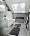 Bagno moderno con piastrelle grigie, lucernario e arredamento minimalista. Nolte SPA.