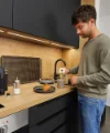 Un uomo prepara il caffè in una cucina moderna di Nolte Kitchen.