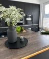 In una cucina moderna con armadi scuri, un vaso di fiori è sul piano di lavoro. Nolte Kitchen.