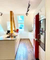 Cucina moderna con accenti rossi ed elementi in legno, illuminata da lucernari. Nolte Kitchen.