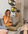 Donna seduta su un divano con un laptop in una stanza moderna. Nolte Living.