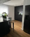 Cucina moderna con mobili scuri e pavimento in legno di Nolte Kitchen.