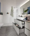 Bagno moderno con grande specchio e cassetto aperto di Nolte SPA.