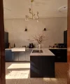 Cucina moderna con isola e armadi scuri, illuminata da un lampadario. Nolte Kitchen.