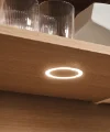 Un placard de cuisine en bois éclairé avec des verres et un bol blanc. Express Küchen.