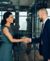 Due persone in abiti da lavoro si stringono la mano in un ufficio moderno.