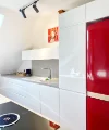 Cucina moderna con accenti rossi, armadi bianchi lucidi e isola. Nolte Kitchen.