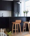Cucina moderna con armadi neri e sedie in legno, design di Nolte Kitchen.