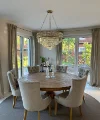 Sala da pranzo elegante con tavolo rotondo in legno e sedie imbottite sotto un lampadario. Nolte Living.