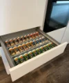 Un cassetto della cucina aperto con barattoli di spezie in un ambiente moderno di cucina Nolte.