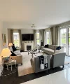 Un soggiorno con divani e poltrone, decorato con cuscini e coperte. Nolte Living.