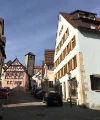 Una pittoresca strada del centro storico con case a graticcio e un campanile sullo sfondo.