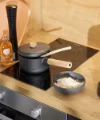 In una cucina moderna con dettagli in legno c'è un fornello con pentola e ciotola di riso. Nolte Kitchen.