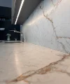 Cucina moderna con piano in marmo e lavello, illuminata da luce sottopensile. Nolte Kitchen.