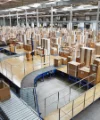 In un grande magazzino, numerosi pezzi di legno imballati sono su nastri trasportatori.