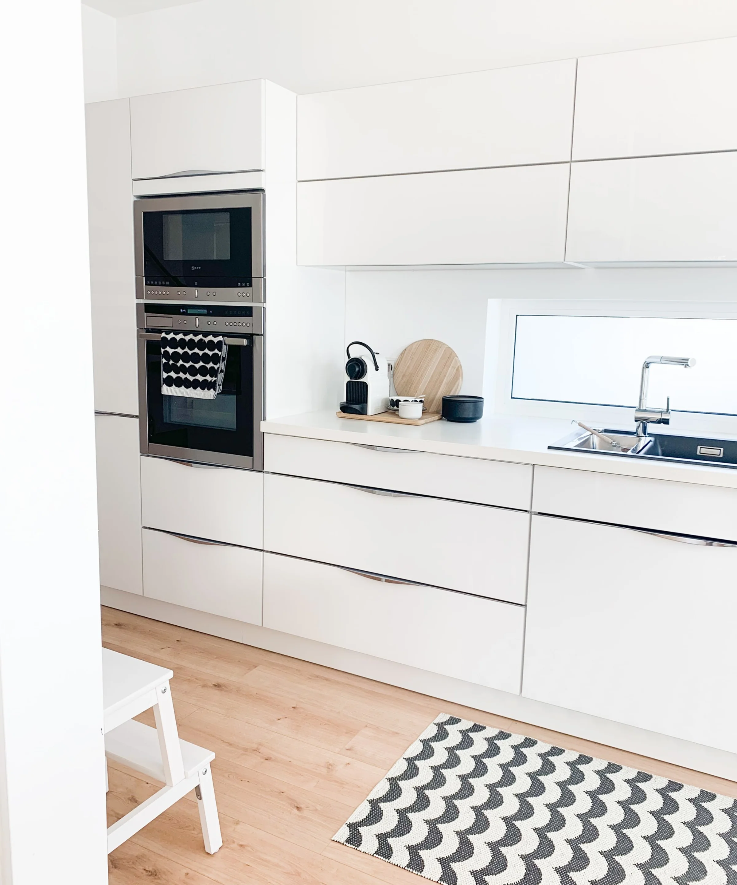 Cucina moderna e luminosa con armadi bianchi e tappeto, progettata con stile da Nolte Kitchen.