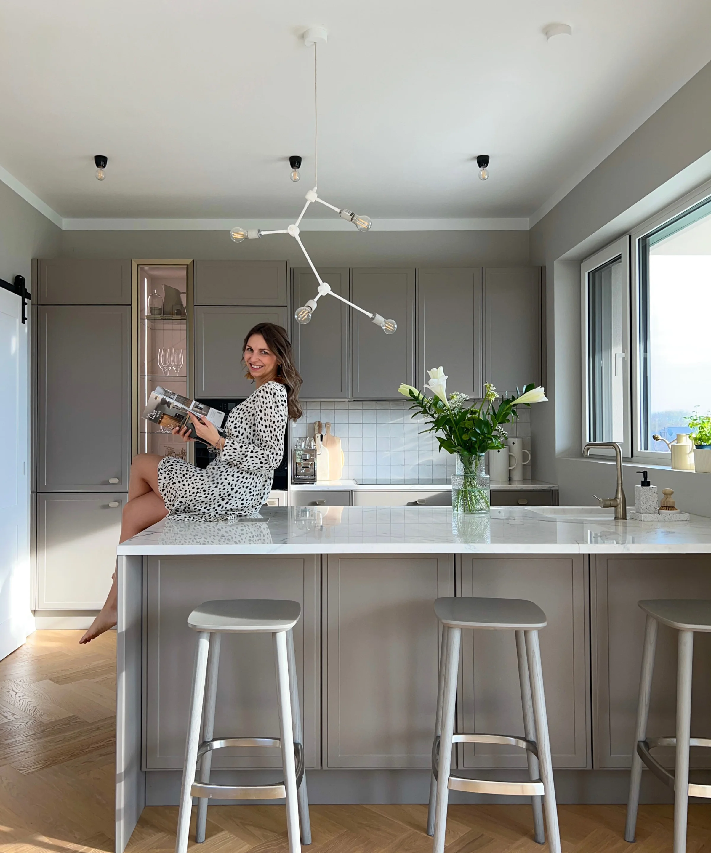 Una donna è seduta su un'isola cucina moderna con fiori, Nolte Kitchen.