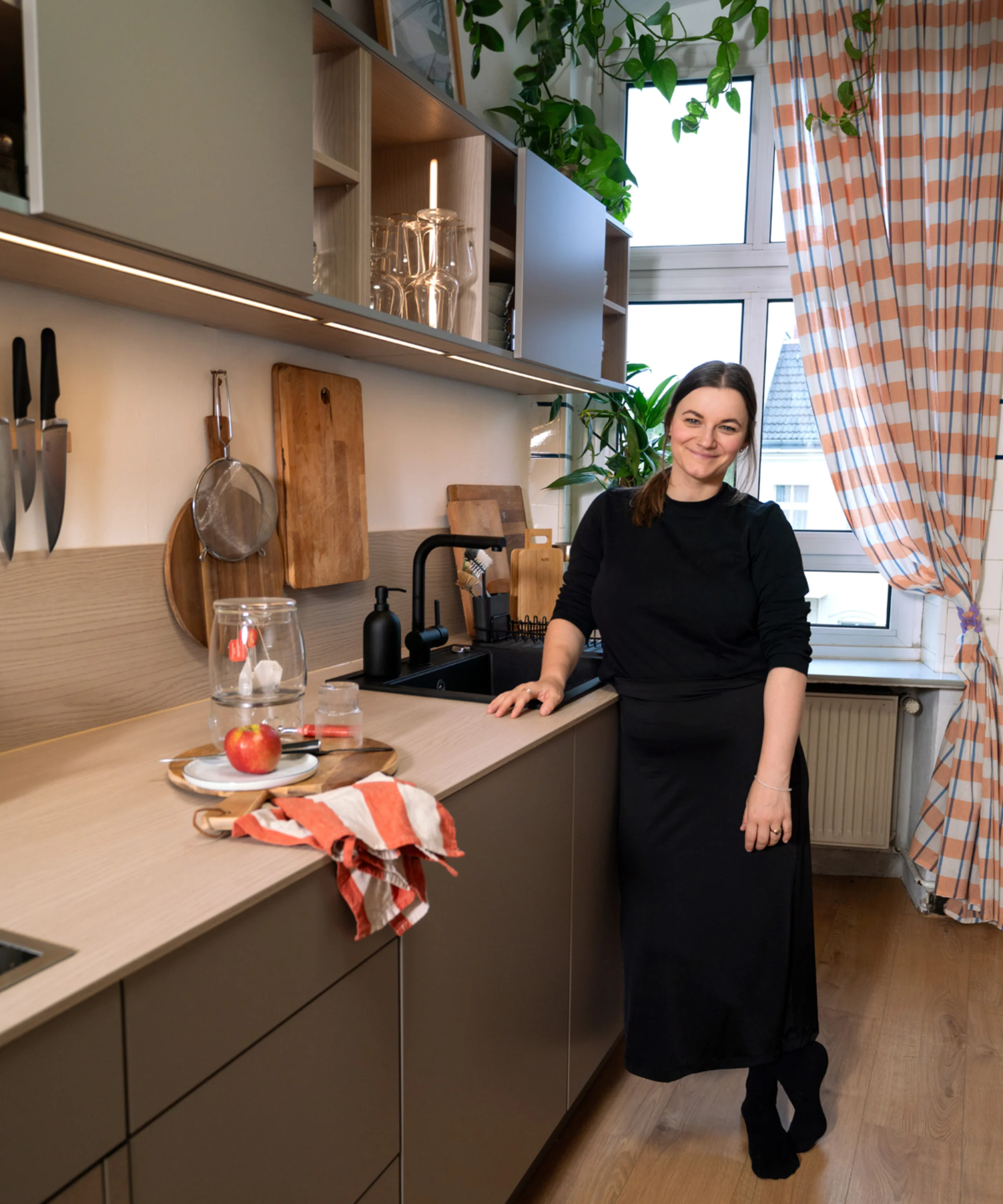 In una moderna cucina Nolte, una donna è al bancone con un tagliere e bicchieri.