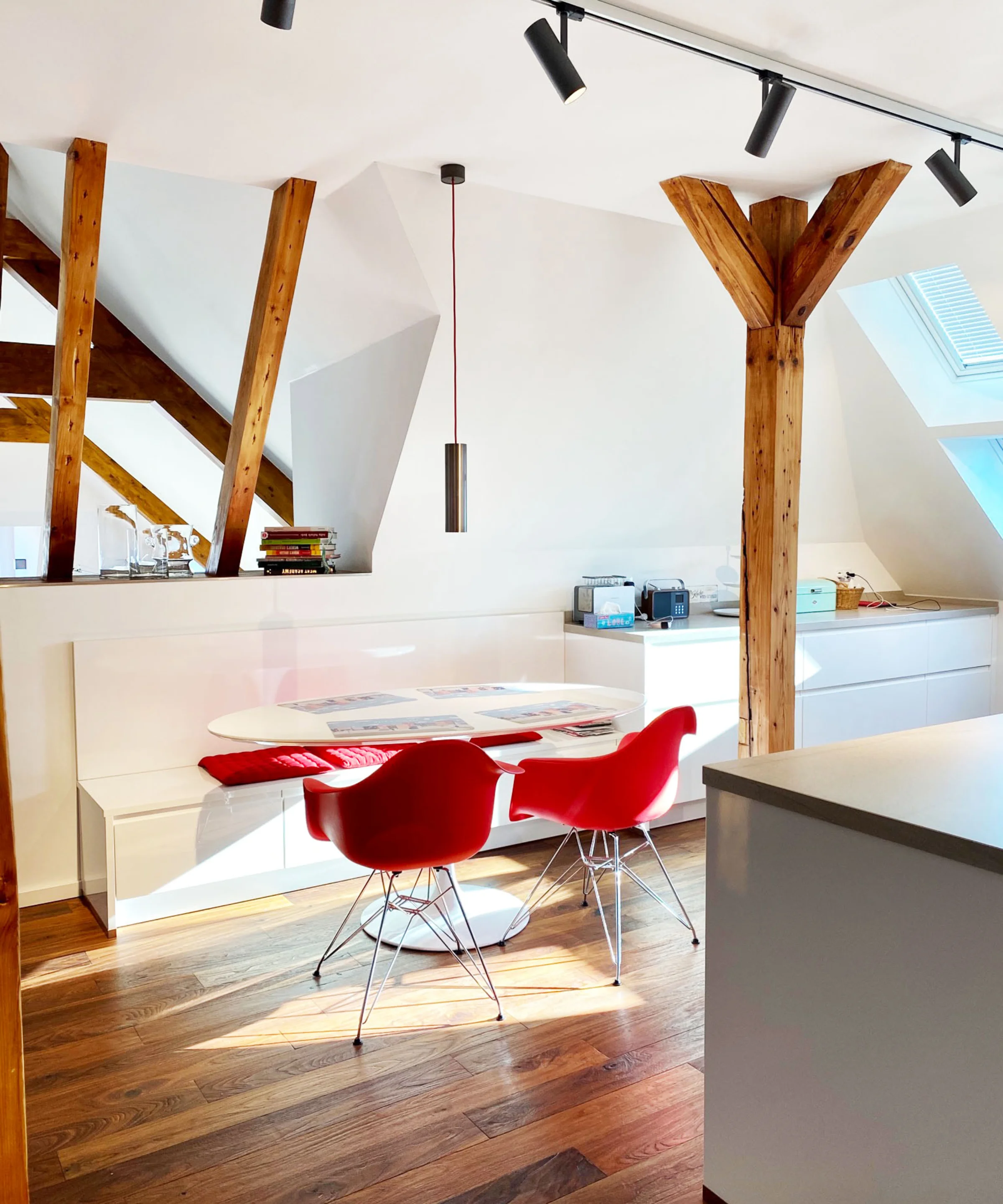 Cucina moderna con travi in legno e sedie rosse sotto una finestra sul tetto. Nolte Kitchen.