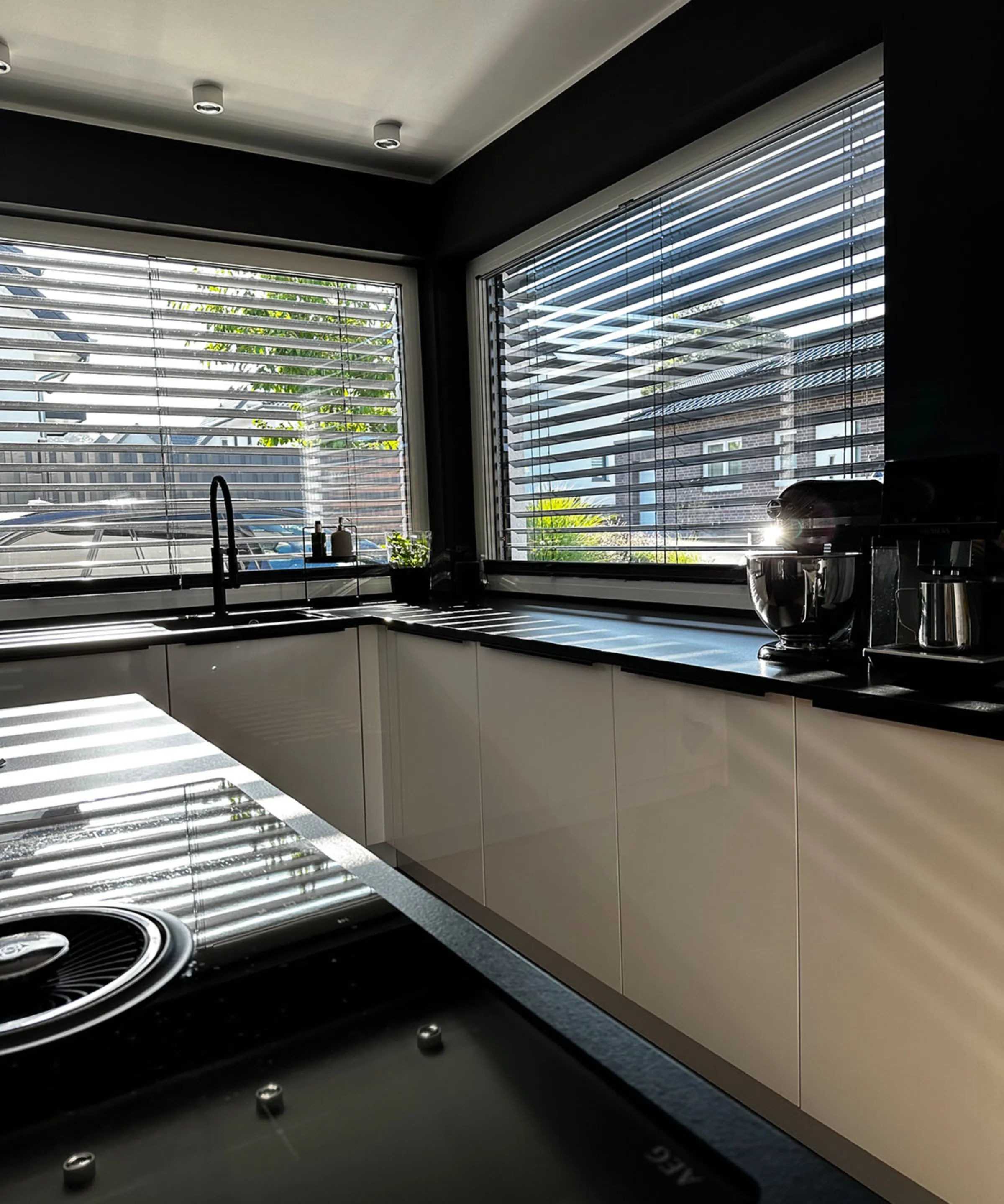 Una cucina moderna con armadi bianchi e grandi finestre che lasciano entrare molta luce. Nolte Kitchen.