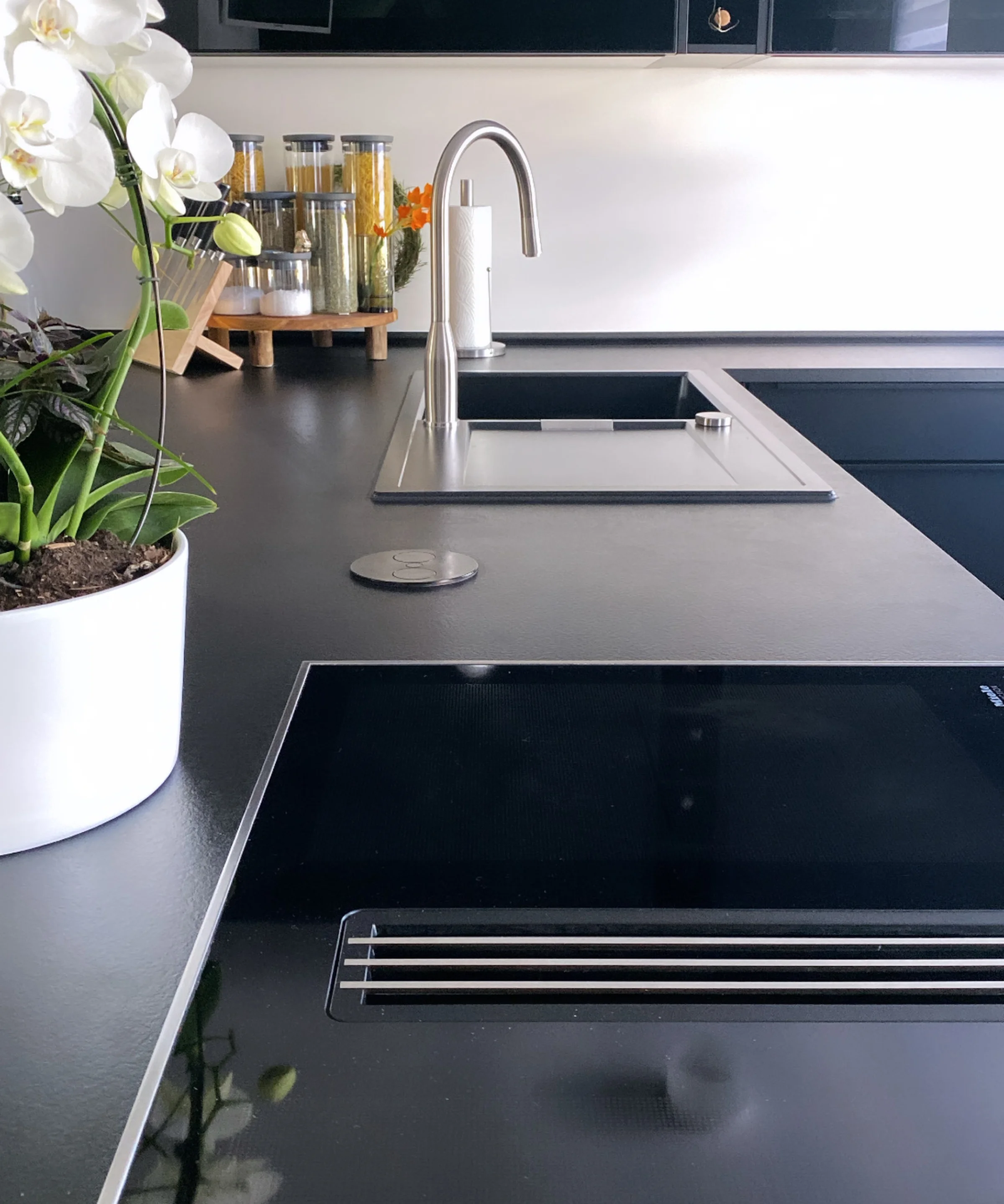 Cucina moderna con piano nero e orchidee bianche, Nolte Kitchen.