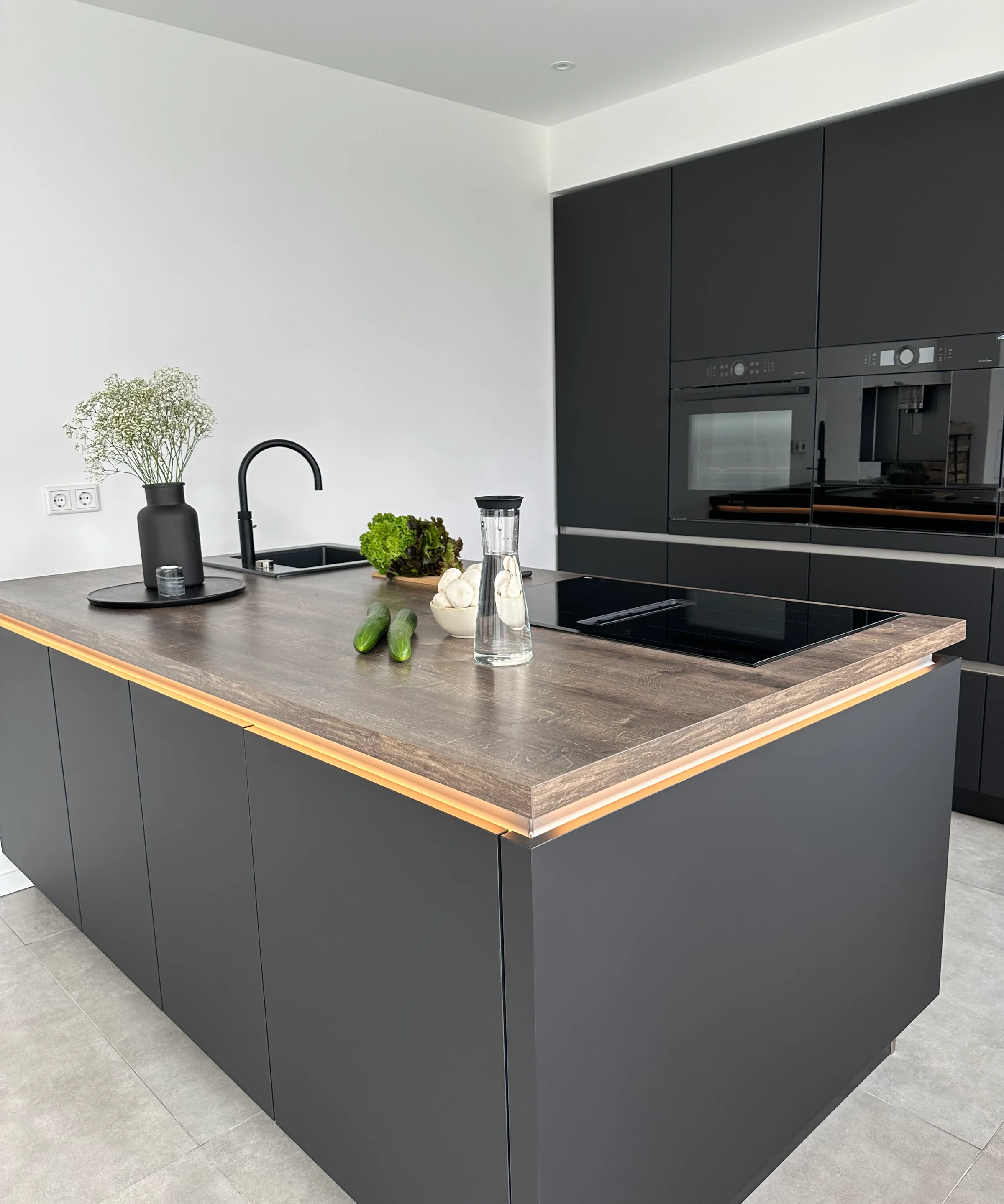 Cucina moderna con armadi scuri e accenti in legno, arredata da Nolte Kitchen.