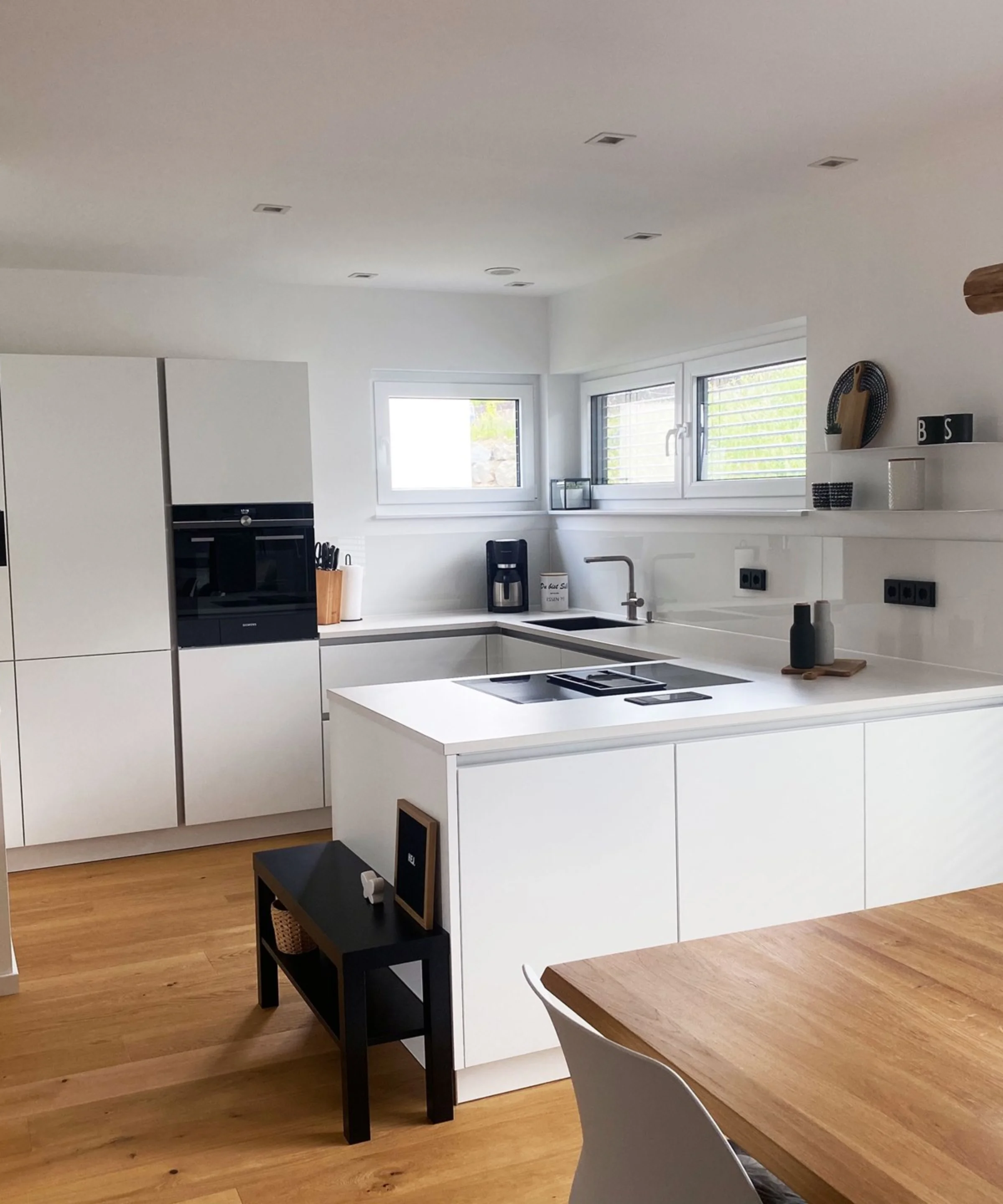 Cucina moderna bianca con dettagli in legno e isola, arredata da Nolte Kitchen.