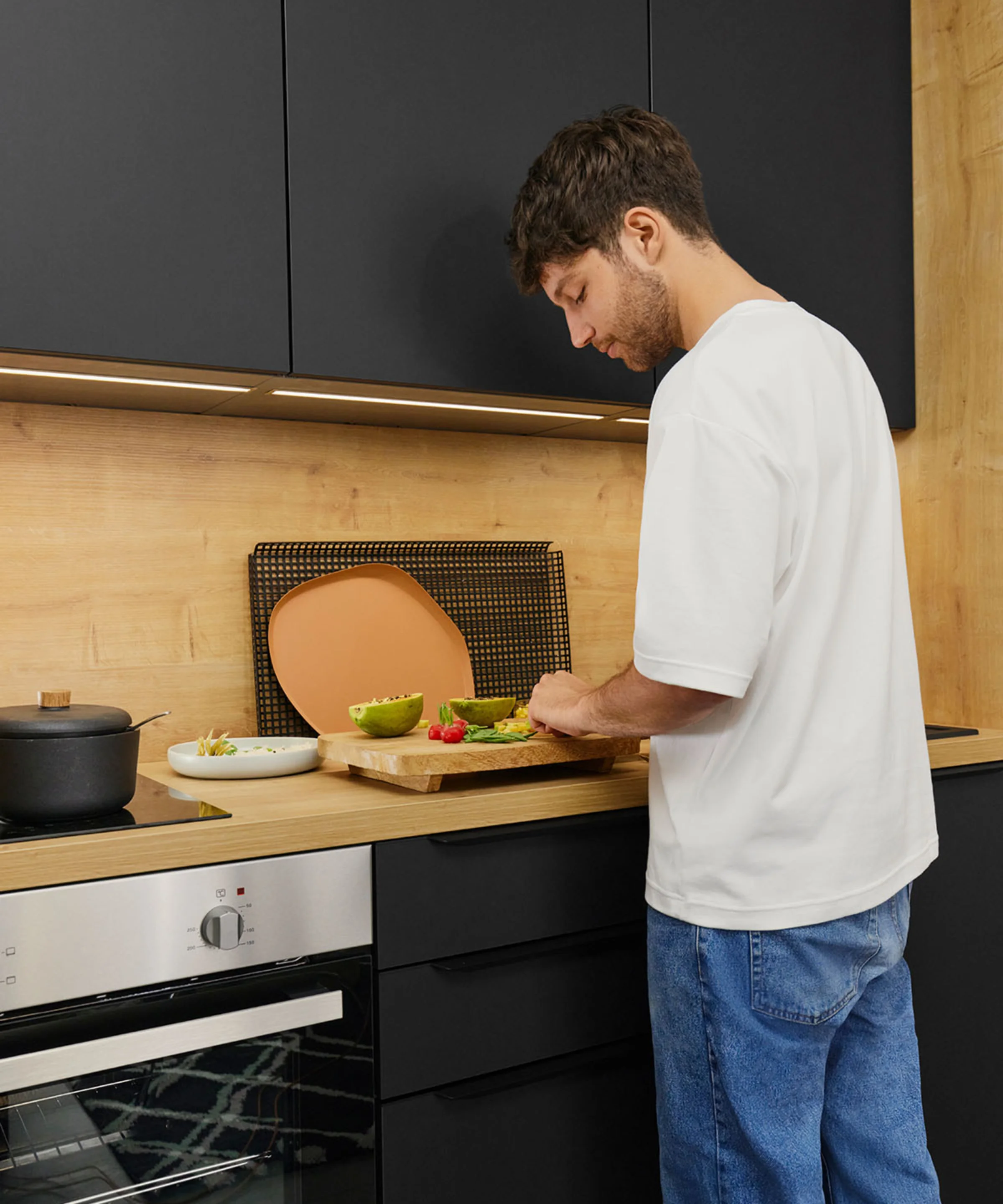 Un uomo taglia verdure in una cucina moderna con armadi neri. Nolte Kitchen.