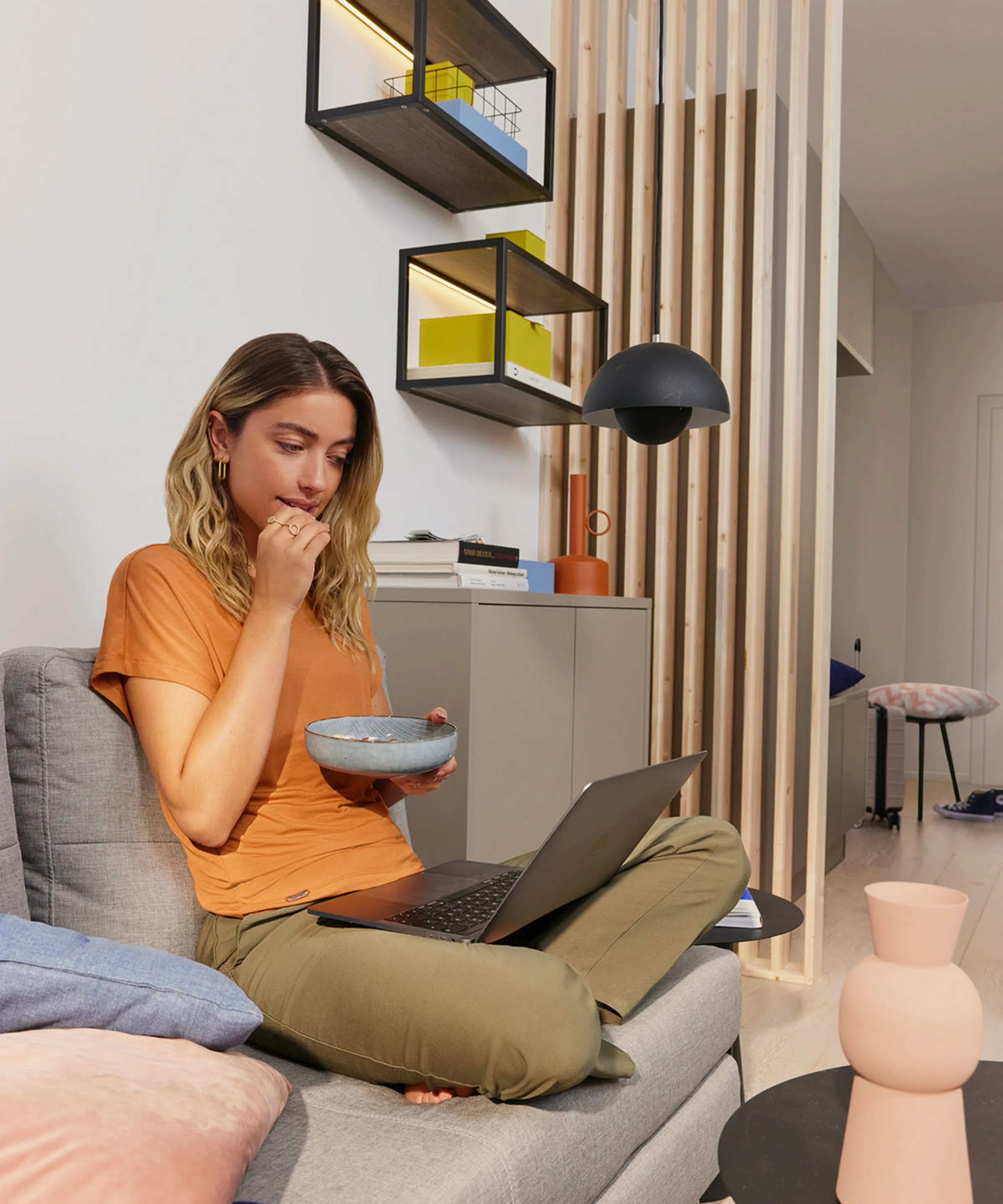 Donna seduta su un divano con un laptop in una stanza moderna. Nolte Living.